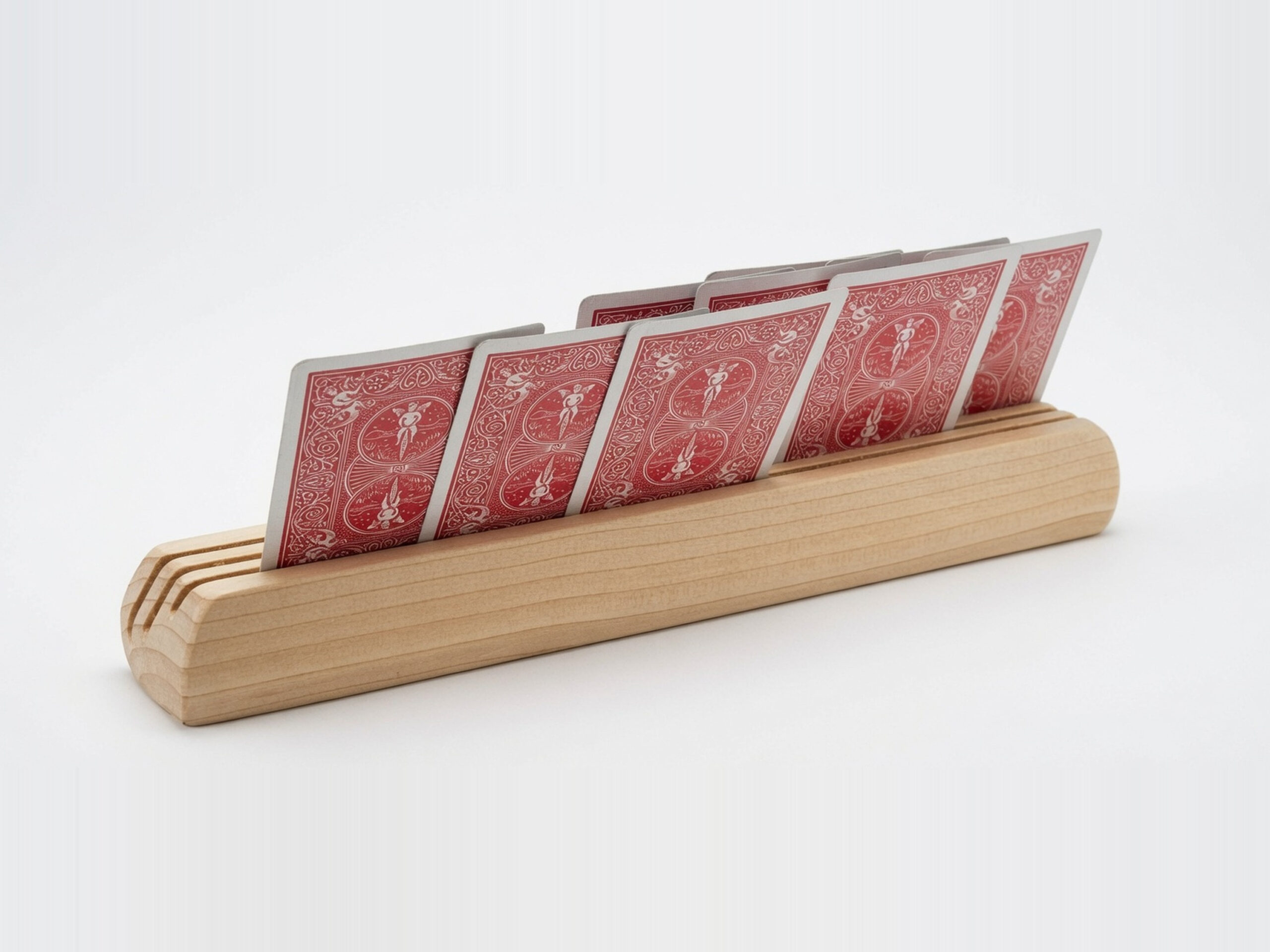 Rear three-quarter view of a wooden playing card holder made from fir, with red-backed playing cards positioned in three angled slots.