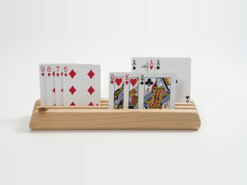 Front view of a wooden playing card holder made from fir, with face-up cards visible in three tiered rows.