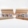 Ten wooden playing card holders made from fir on a white background, with two holding face-up cards and eight holders stacked behind them.